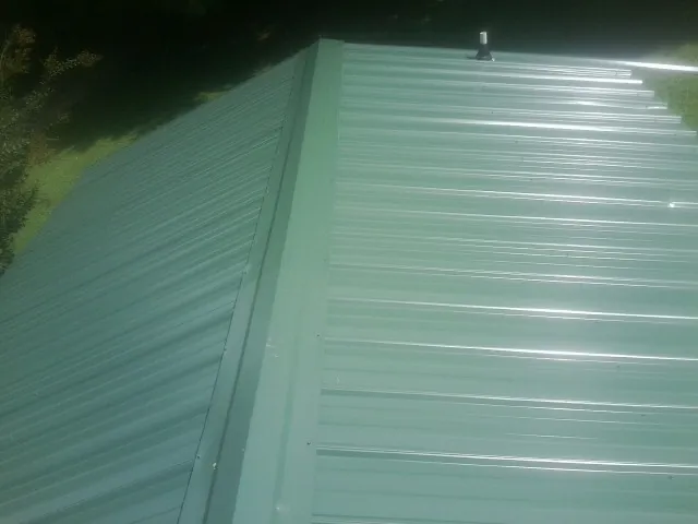 New green metal panels meeting at the ridge of a roof — Flat Roof Repair work by our crew in Boulder