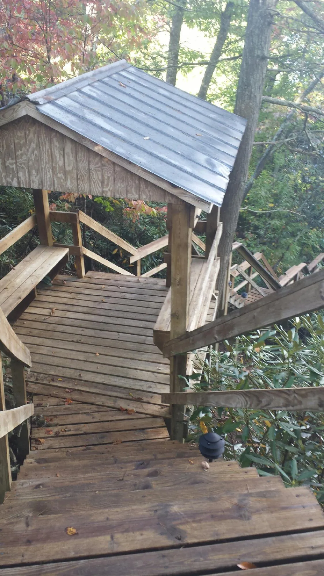 Metal roofed shelter over wooden steps on a wooded walkway — Skylight Repair & Installation work by our crew in Boulder