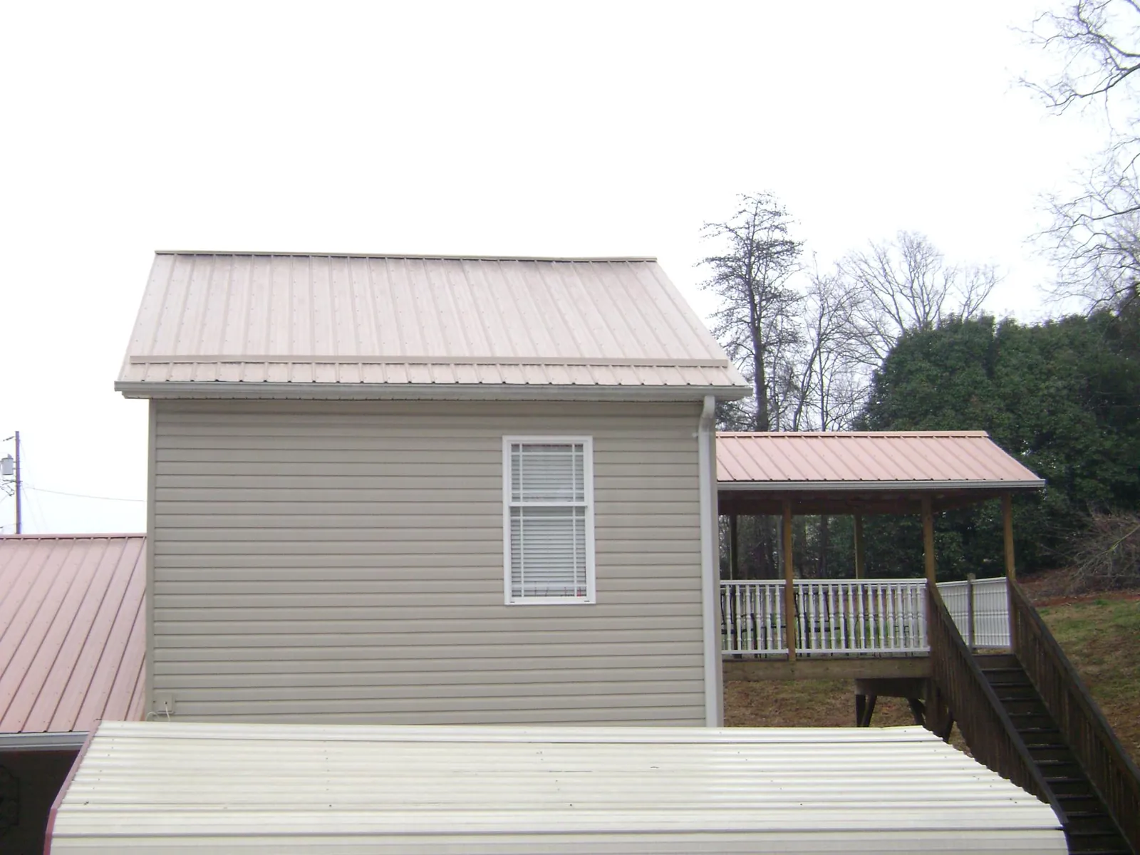 Tan metal roofs on a two story addition and attached porch, from a Roof Replacement job in Boulder