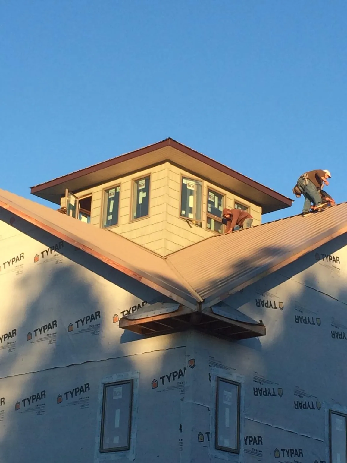 Roofers working around a rooftop cupola on a new metal roof at sunset — Roof Waterproofing in Boulder by Roofing Brothers